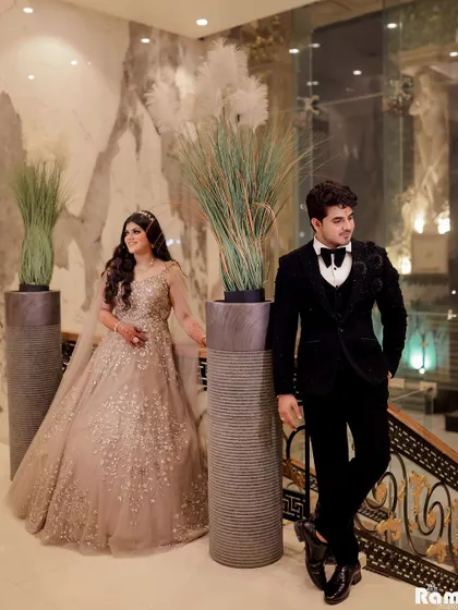A stylish portrait of the couple at their engagement venue. The grand staircase and modern decor provide a sophisticated backdrop for their elegant attire.