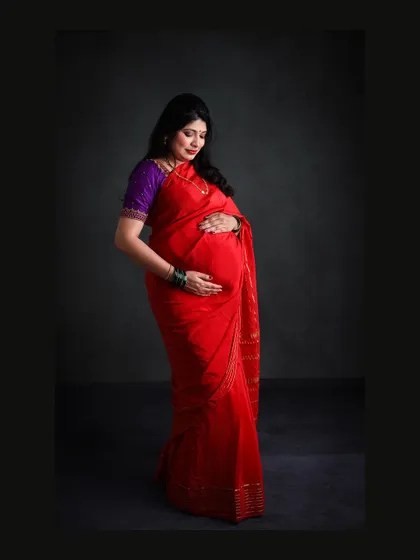 A classic low-key portrait in a vibrant red saree. The dark background makes the color of the saree pop and creates a dramatic, focused image.