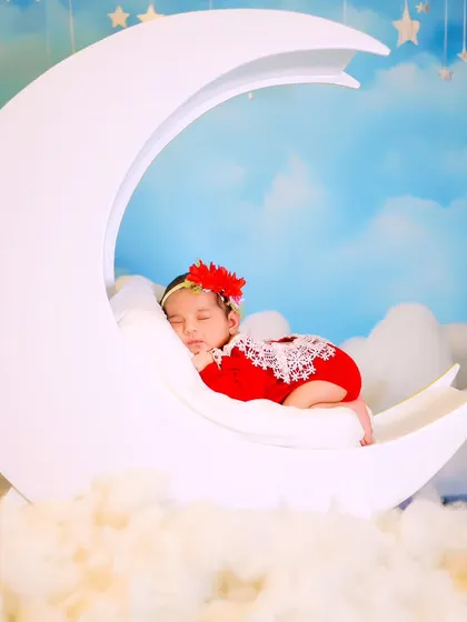 A wider angle of the newborn on the white moon prop, showing the dreamy cloud and sky setup in our studio.