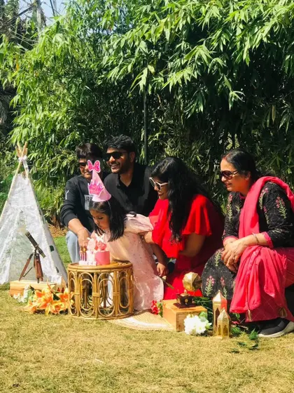 A family celebrating a birthday with a small cake during their intimate picnic gathering.