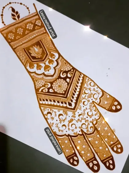 This elegant bridal design features a lotus and jhumkha (bell) motif at the wrist, flowing into a delicate vine pattern on the palm. The finger details complete this graceful look.
