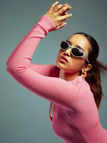 A dynamic shot capturing movement. The model's pose and the slight motion in her hair add energy to this studio fashion portrait, showcasing the outfit in an active, engaging way.