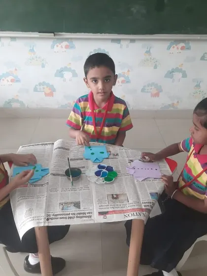 Three students collaborate on their Father's Day crafts, learning and creating together.
