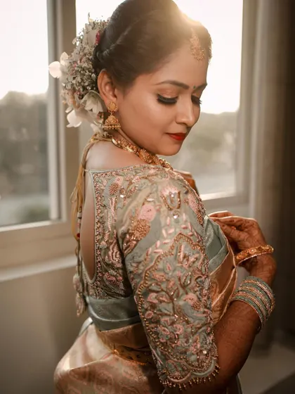 A sun-kissed portrait of a bride showing the detailed embroidery on the back of her blouse and the flowers in her hair. We capture the artistry of every element of the bridal look.