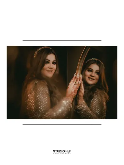 A beautiful portrait of the bride looking at her reflection in a vintage mirror. The warm, soft lighting creates an intimate and timeless feel.