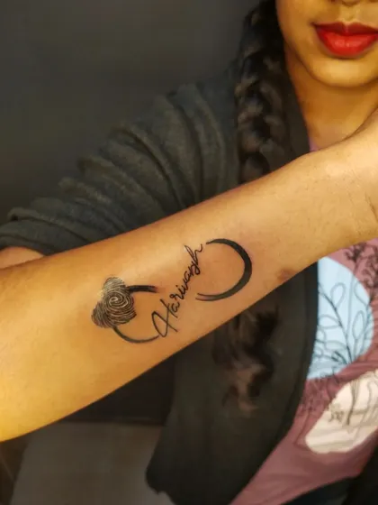 This tattoo weaves the name "Harivansh" into an infinity symbol that ends in a rose. It's a creative way to symbolize eternal love.
