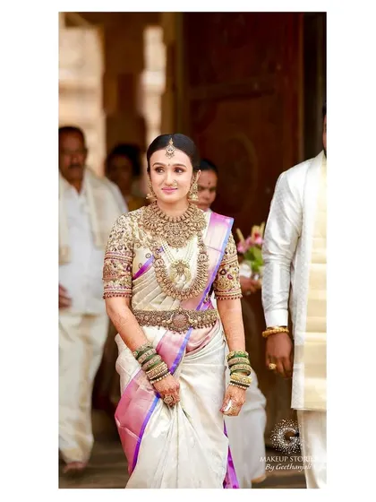 Vishnu Priya walking through the temple corridor. Her posture is graceful, and her entire look, from the perfectly draped saree to the flawless makeup, is a picture of bridal elegance.