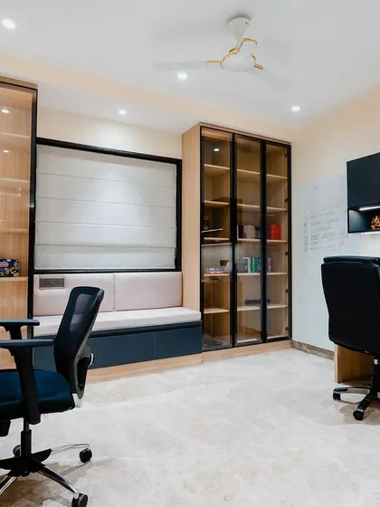 Another view of the spacious study room, showing the two workstations and the ample storage provided by the glass-front cabinets.