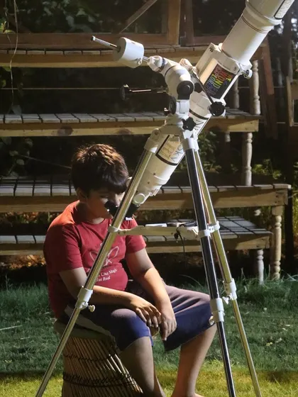 A young explorer sitting patiently by the telescope, ready for his journey to the stars.