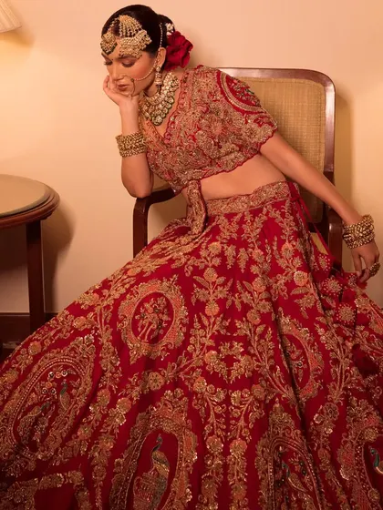 Presenting Nazaakat. A bride in a heavily embroidered red lehenga, seated in a vintage-inspired setting.