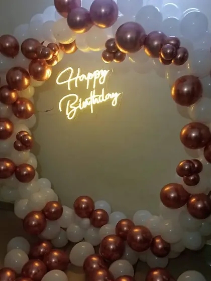 A beautiful birthday surprise setup in Noida. The ring arch made of white and rose gold chrome balloons with a neon sign is a very popular and elegant choice.