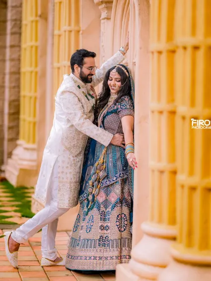 A romantic and playful moment between a couple in a beautiful, sunlit corridor. The groom's gesture and the bride's smile make this a very special candid shot.