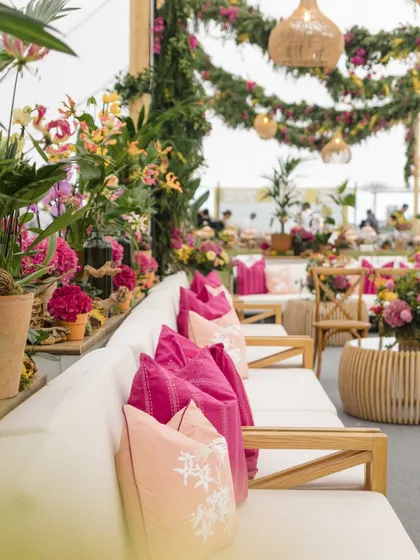 The English countryside Mehendi, filled with lush, colorful florals, comfortable lounge seating with bright pink cushions, and charming wicker details.