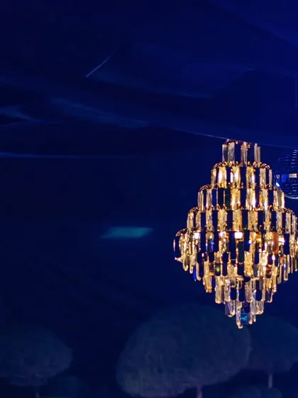 The warm light from the crystal chandelier contrasts beautifully with the deep blue of the draped ceiling.