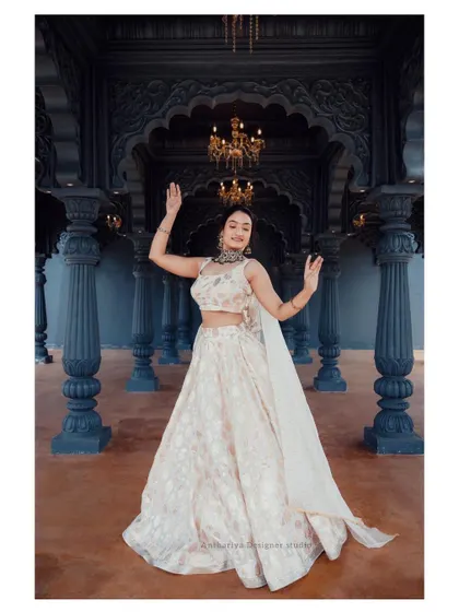 A model in an elegant off-white lehenga with subtle gold patterns, exuding grace and sophistication.