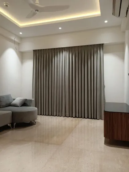 A serene and modern living room featuring a custom grey sectional sofa. The full-length grey curtains and minimalist decor create a calming and sophisticated environment, perfect for relaxation.