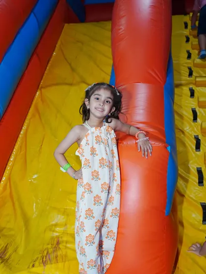 A girl strikes a pose at the top of an inflatable climbing slide, ready to zip down.