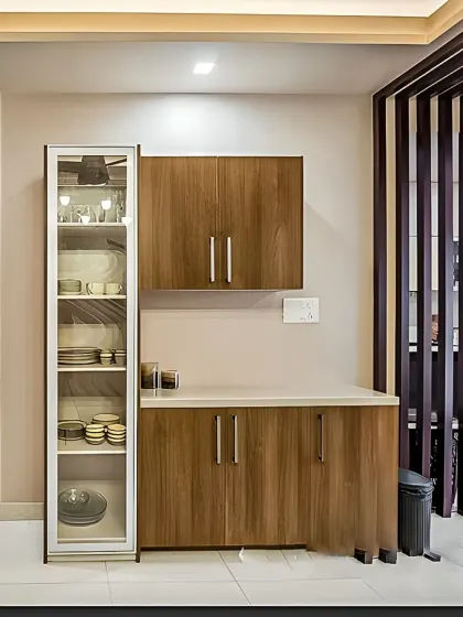 A simple and clean crockery unit setup next to a kitchen entrance. The design includes a tall glass-door cabinet for display and a matching wooden sideboard for concealed storage.