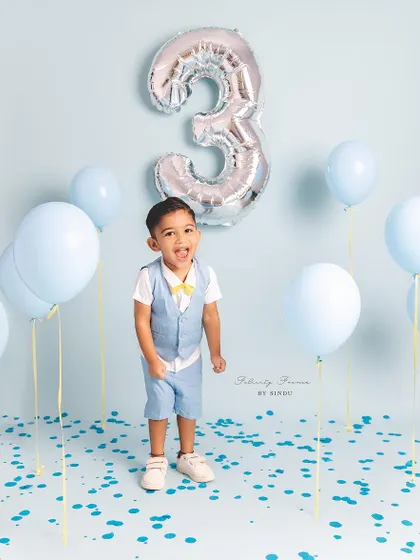 Another joyful shot of this three-year-old celebrating his birthday with blue balloons and confetti.