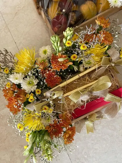 Another example of a wedding gift platter. Here, gift boxes are nestled in a bed of hay and surrounded by a colorful floral arrangement, tied with golden ribbons.