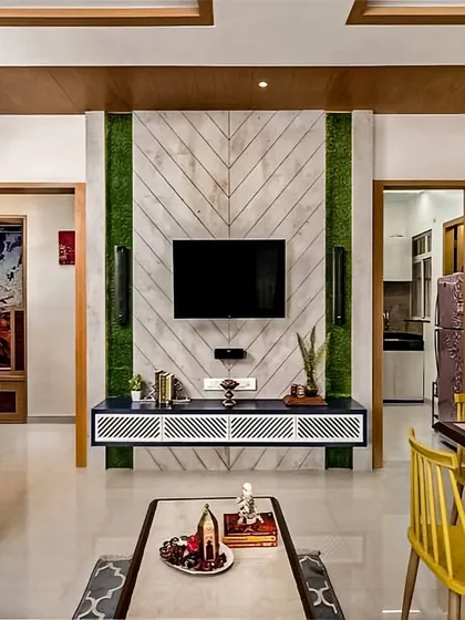 A unique TV wall design featuring a chevron-patterned wood panel flanked by vertical green strips that mimic a living wall. The floating white console adds a modern, airy contrast to the natural textures.