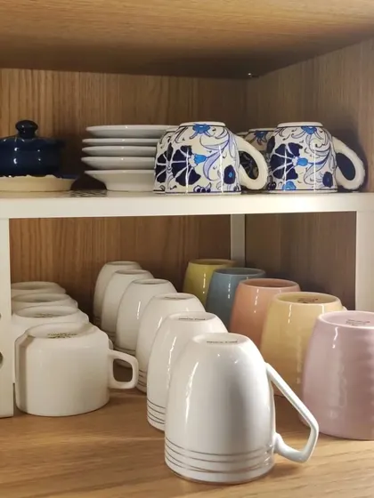 This image shows how a simple white shelf riser can instantly create more usable space in a cabinet, allowing you to stack mugs and small plates without risk of damage.