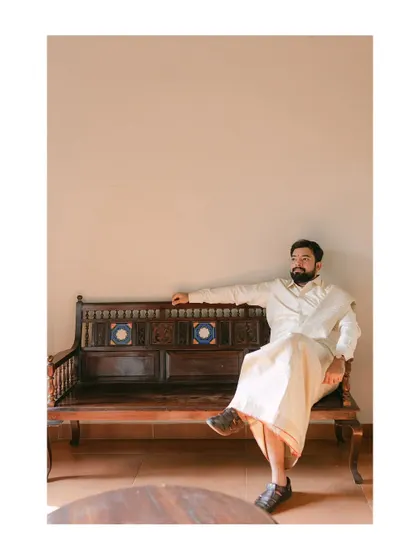 A groom in traditional South Indian attire, relaxing on a carved wooden bench. This portrait captures his calm and composed demeanor with a touch of classic style.