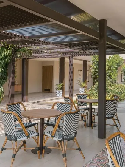 The interplay of light and shadow from the pergola creates beautiful patterns on the ground, adding a dynamic element to the space.