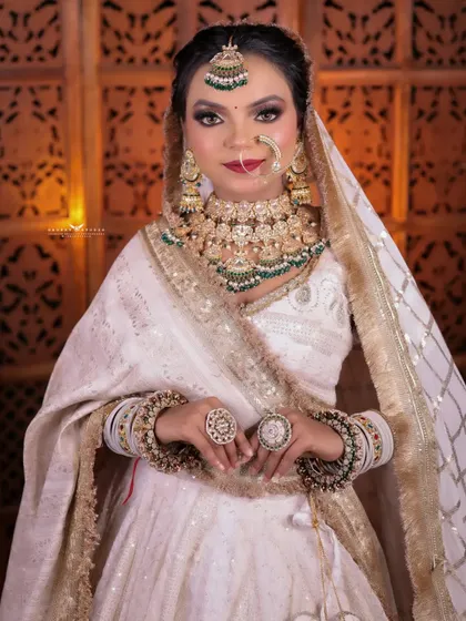 A beautiful portrait with the bride's hands clasped in front. The focus is on her serene expression and the stunning combination of her white outfit and heavy kundan jewellery.