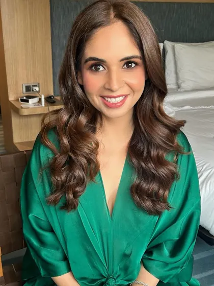 A happy client showing off her final look. The combination of voluminous hair and fresh, radiant makeup creates a look that is both beautiful and approachable.