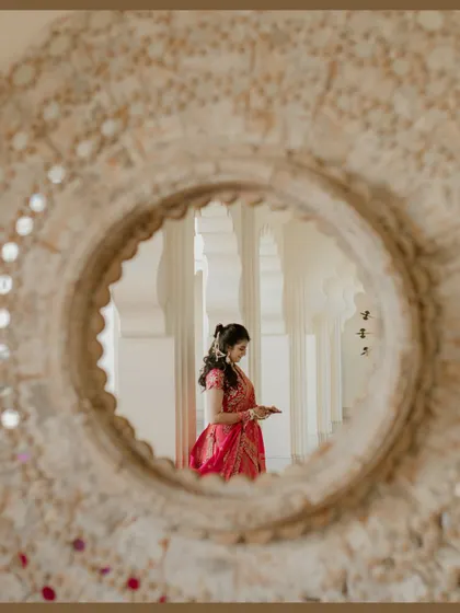 A creative portrait of the bride seen through a circular mirror. This unique framing adds an artistic touch to her Haldi day look in Udaipur.