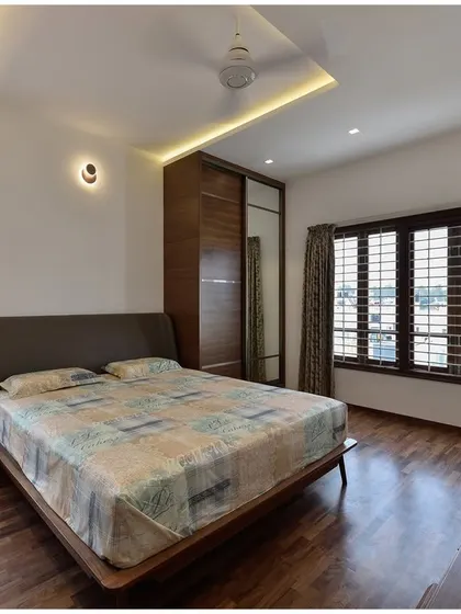 This bedroom is designed for comfort and functionality, with large windows for ventilation, a built-in wardrobe with a mirror, and a dedicated study desk.