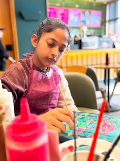 A young girl concentrating on her forest painting. It's inspiring to see such focus and dedication.