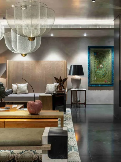 A view of the formal living room highlighting a large daybed, a sculptural cherry accent, and a traditional rug hung as a tapestry on the wall. The space is a testament to our eclectic and layered approach to curation.