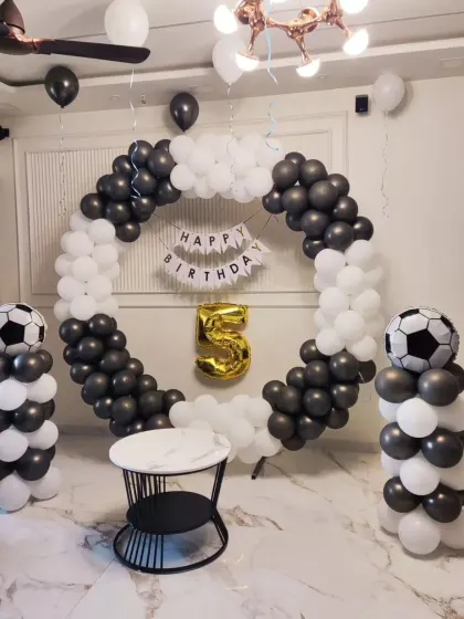 A football-themed 5th birthday with a black and white balloon ring and football-print balloons.