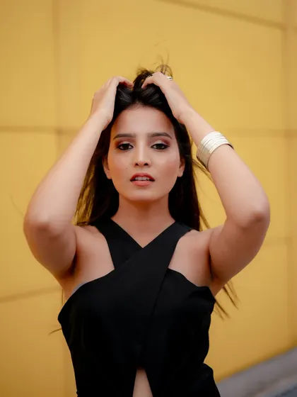A duplicate of image 410, this portrait against a yellow wall uses a metal pole as a prop to create a modern and graphic fashion shot.