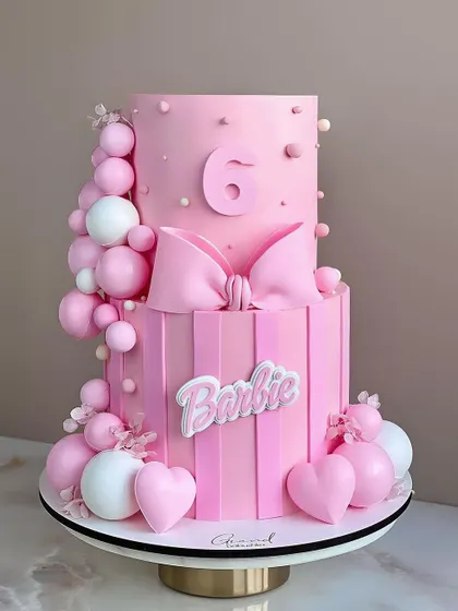 A gorgeous two tier Barbie cake in shades of pink. The large bow, hearts, and balloon details make this a super stylish and girly celebration cake.