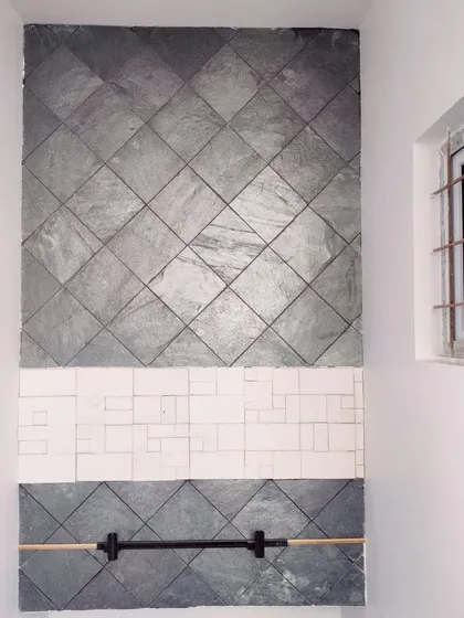 A direct shot of the staircase wall cladding, highlighting the texture and pattern of the grey and white tiles.