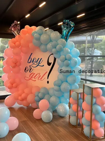 A classic "Boy or Girl?" gender reveal party setup. A circular frame is filled with pink and blue balloons, creating a perfect backdrop for the big announcement.