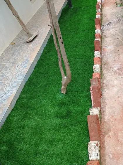 This installation involved laying a strip of artificial turf alongside a tiled walkway, neatly fitting it around existing trees.