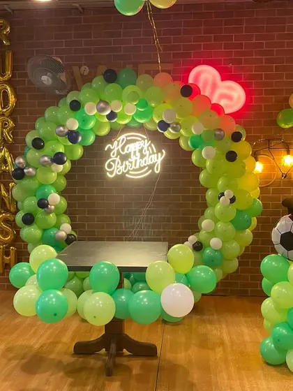 A full view of the football-themed birthday setup, showing the circular balloon arch, pillars, and the name of the birthday boy in foil letters.