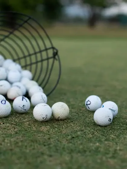 A collection of practice balls on the grass, some marked with numbers for tracking. This shot represents the hard work and repetition that goes into improving your game.