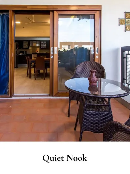 This quiet nook is where peace lives. A small balcony with wicker chairs and a glass-top table provides a charming spot for outdoor me-time, overlooking the home's interior.
