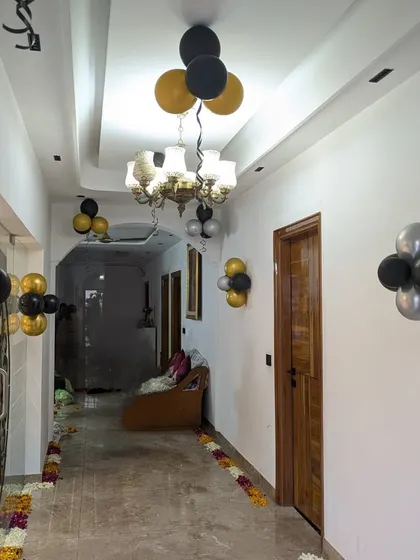 Simple balloon clusters in black, gold, and silver guide guests through the hallway to the main party area.