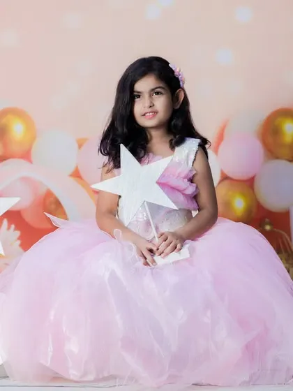A sweet and dreamy portrait of a little princess. The soft pink tones, fluffy dress, and star props create a fairytale-like setting for a birthday or milestone shoot.