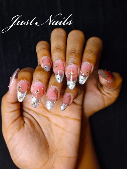 An ethereal design with a sheer pink base, silver glitter tips, and delicate star-like rhinestone and gold bead embellishments.