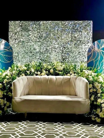Modern, chic, and glamorous. This reception stage combines a shimmering sequin backdrop with artistic teal panels and an abundance of white flowers, creating a contemporary and high-fashion look.