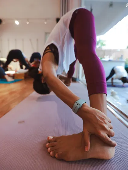A deep forward fold, Padangusthasana (Big Toe Pose), in our studio. This pose helps to lengthen the hamstrings and calm the mind.