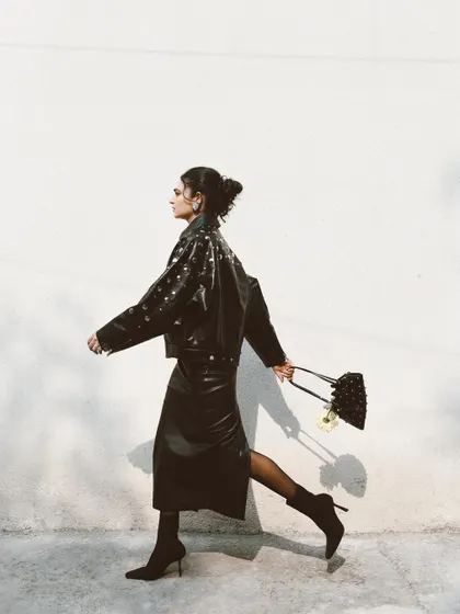 A side-profile shot of Kavya Trehan walking, creating a sense of movement and purpose. This is a classic street-style fashion shot that feels alive.