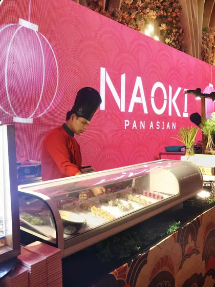 Our "Naoki Pan Asian" sushi station, where a chef meticulously prepares fresh sushi rolls. The station is beautifully branded and lit, becoming a visual and culinary highlight of the event.